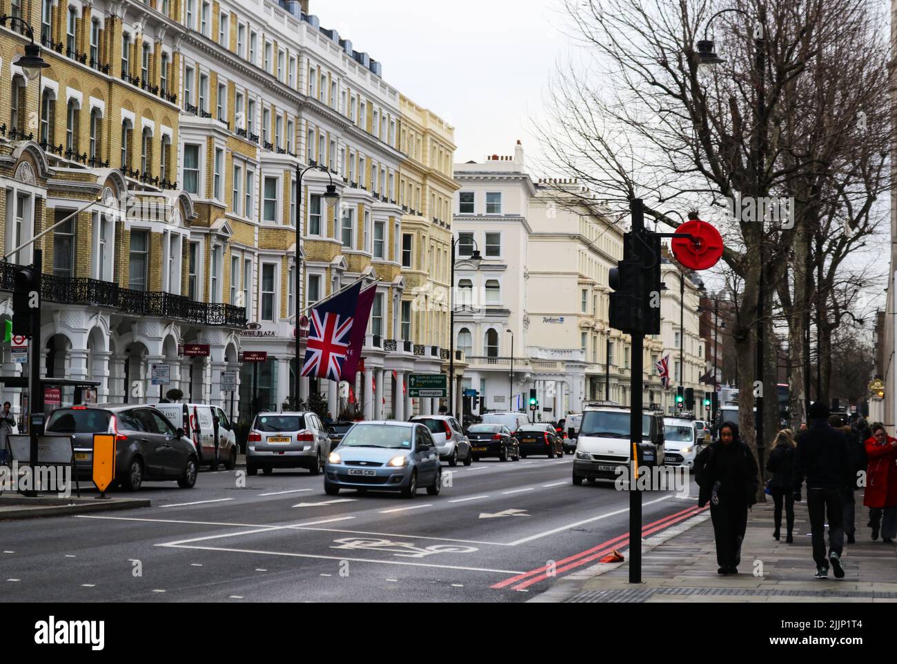 Les gens marchent sur le trottoir de la route dans le sud de Kennsington avec le drapeau britannique volant de l'autre côté de la rue par une journée froide Banque D'Images