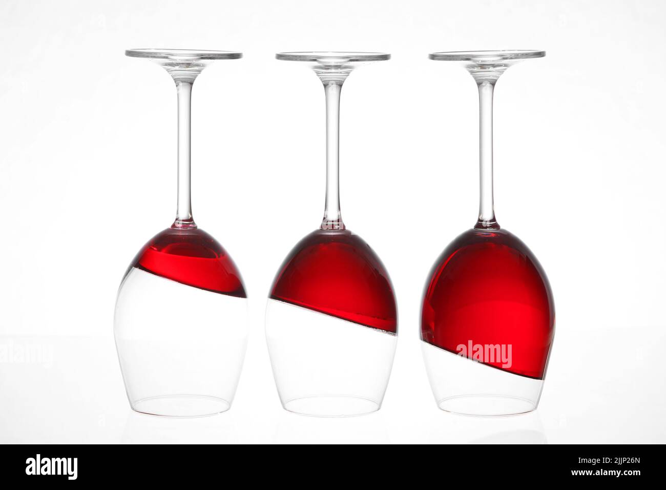 Trois verres à vin inversés avec vin rouge isolé sur fond blanc Banque D'Images