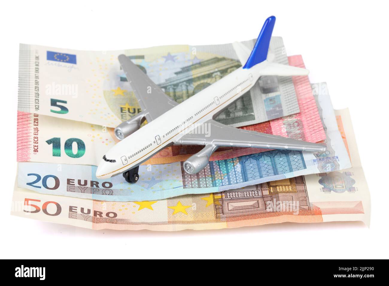 Un jouet d'avion sur des billets en euros isolés sur fond blanc - économisez de l'argent pour voyager Banque D'Images
