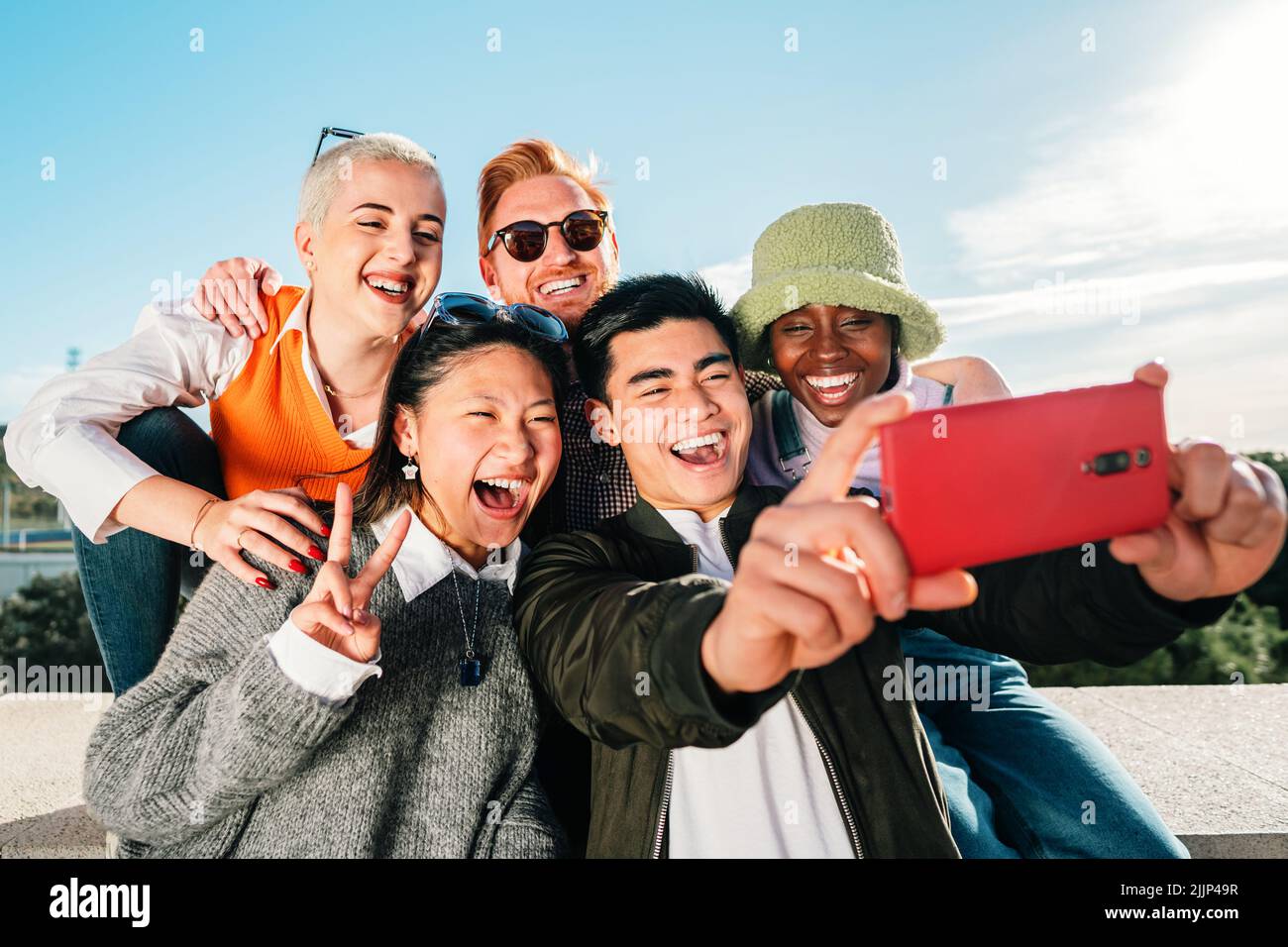 Groupe de jeunes amis multiethniques prenant une photo avec un smartphone. Banque D'Images