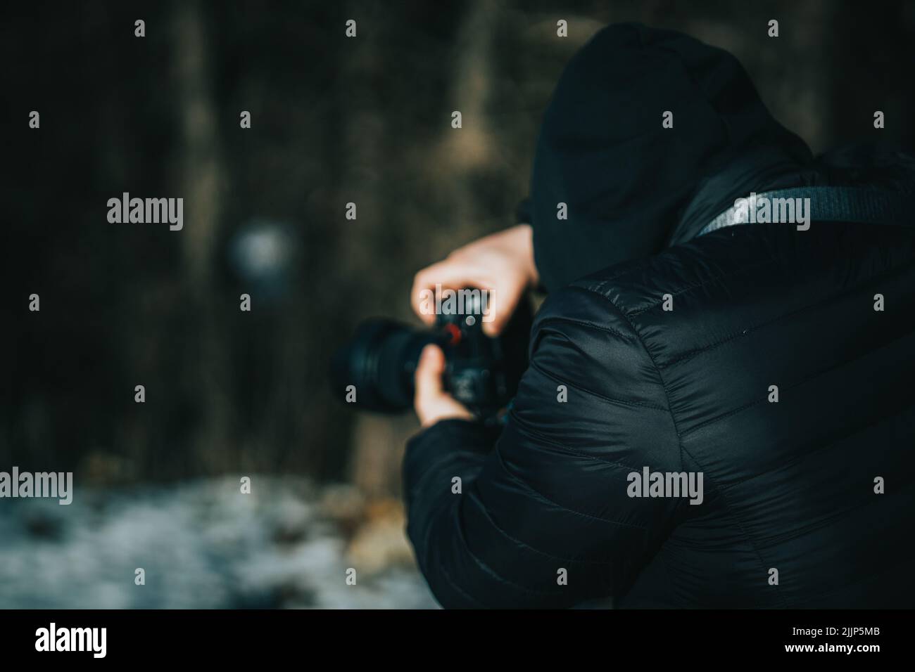 Vue arrière d'un photographe prenant des photos à l'aide d'un appareil photo numérique sur un arrière-plan flou Banque D'Images