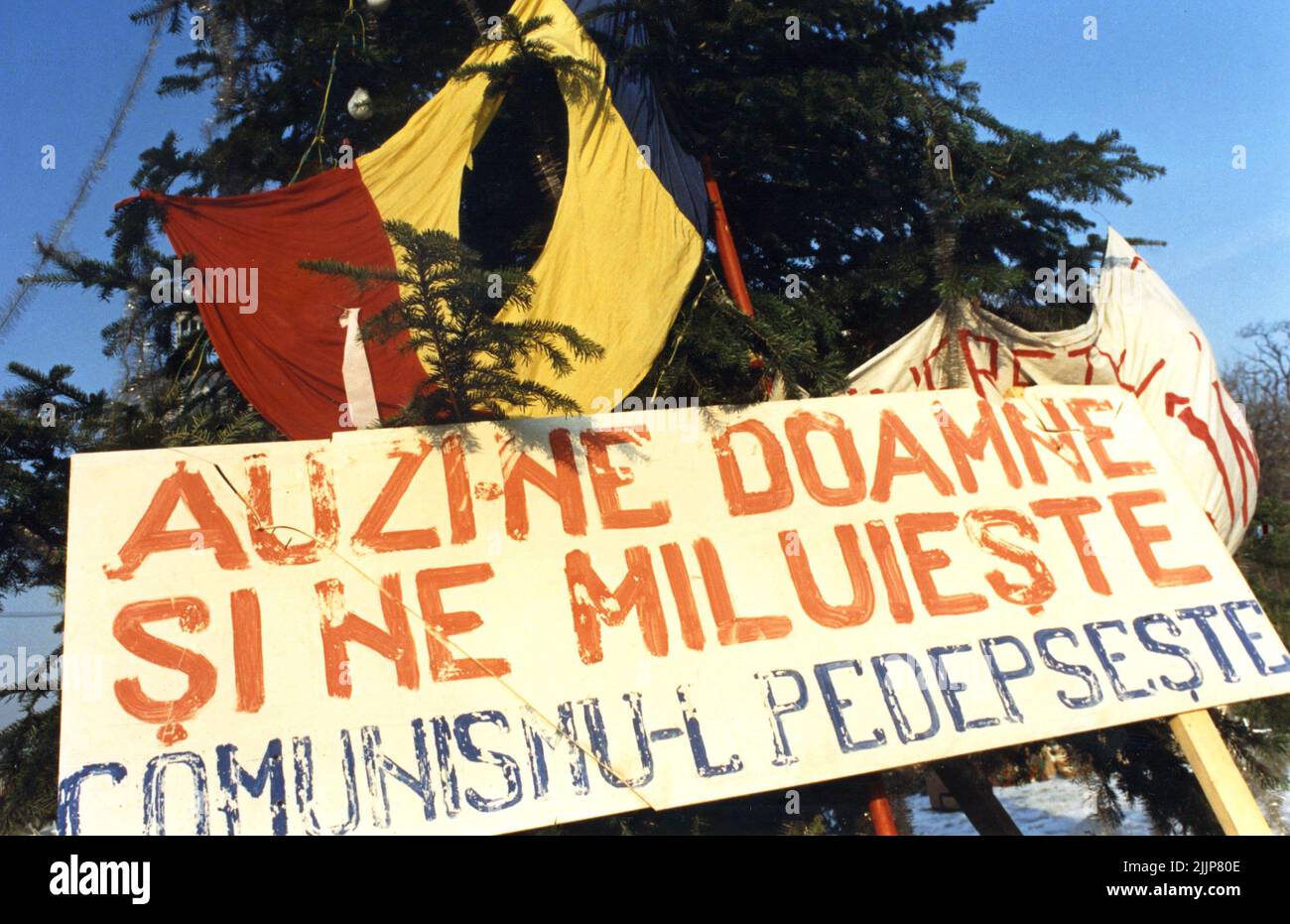 Bucarest, Roumanie, janvier 1990. Mémorial pour les victimes de la révolution anticommuniste roumaine de décembre 1989 sur la place Romana, l'un des points clés du soulèvement. Drapeau roumain coupé avec l'emblème socialiste, un symbole anticommuniste pendant la Révolution roumaine de 1989. Signez disant «nous entendre, Seigneur et avoir miséricorde, punir le communisme». Banque D'Images