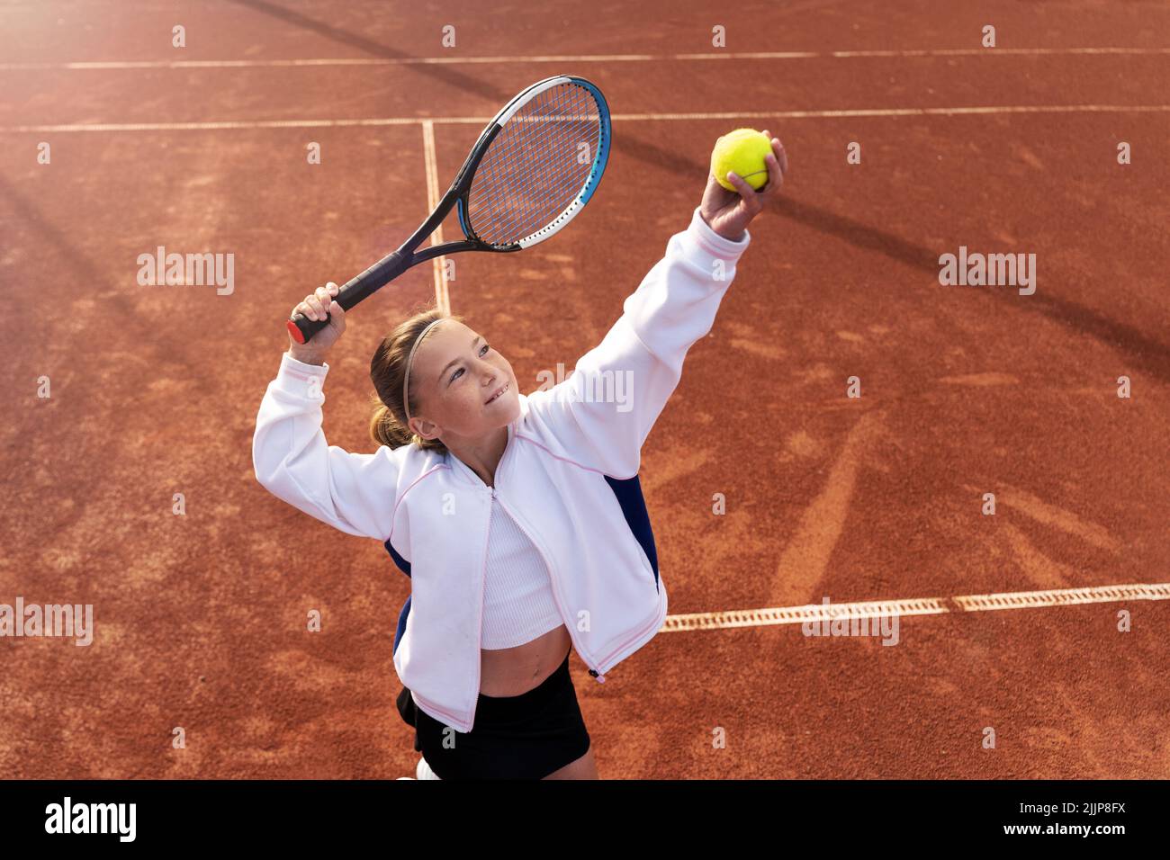 Fille debout sur un court de tennis sur le point de servir Banque D'Images