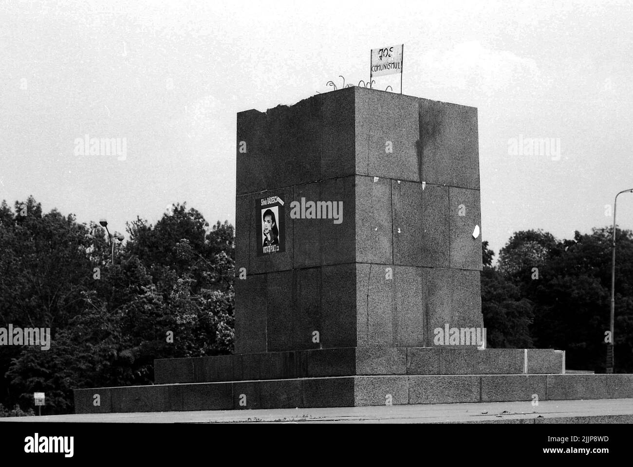 Bucarest, Roumanie, mars 1990. La statue de Lénine est enlevée, ne laissant que le piédestal, trois mois après la révolution anticommuniste roumaine de décembre 1989. La statue se trouvait à Piata Scanteii (la Spark Plazza ) depuis 1960. En haut, quelqu'un a placé une bannière disant « se débarrasser du communisme ». Banque D'Images