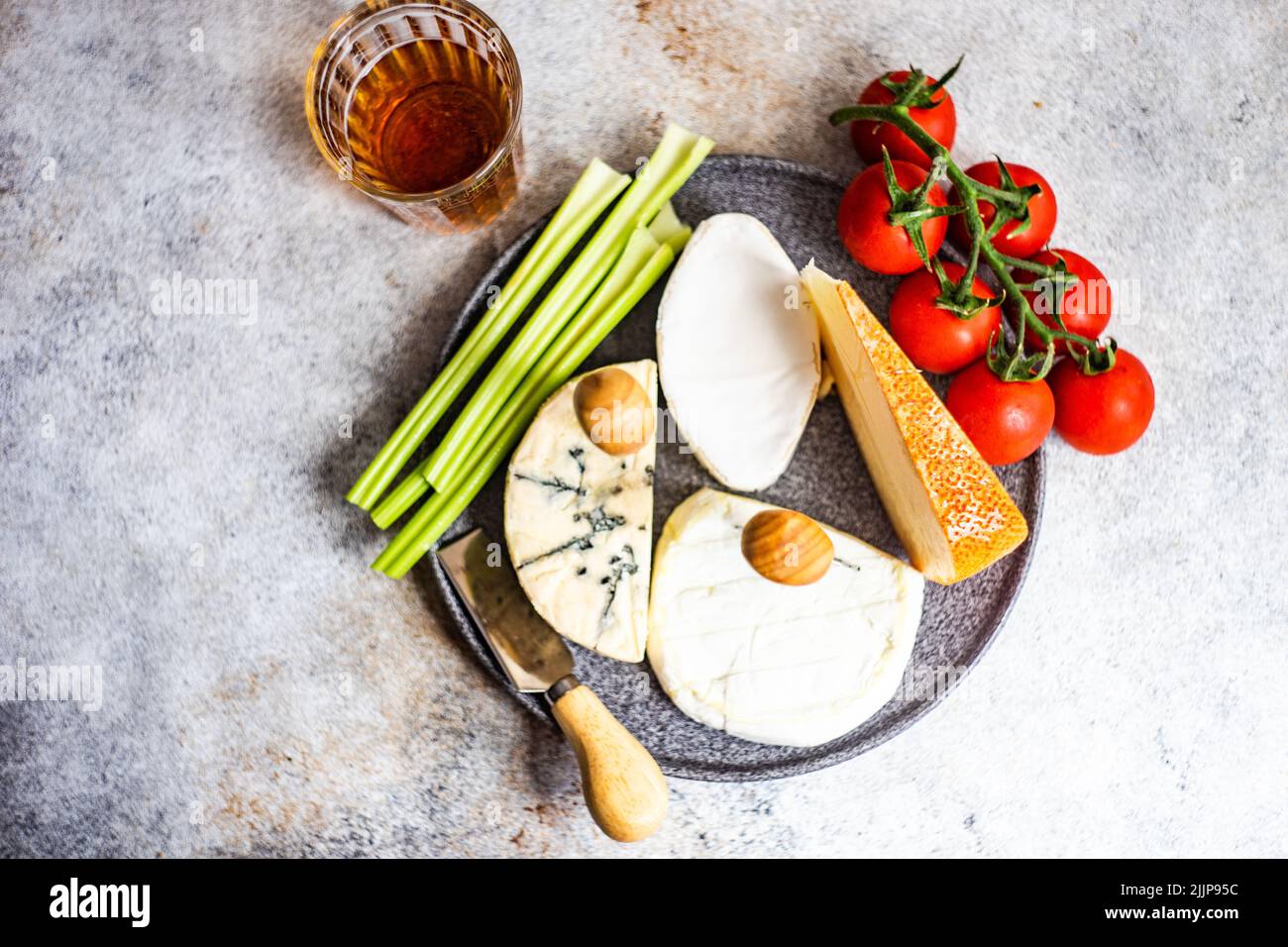 Vue en hauteur de l'assortiment de fromages français avec tomates, céleri et pain sur une planche à découper et un verre de vin dessert Banque D'Images