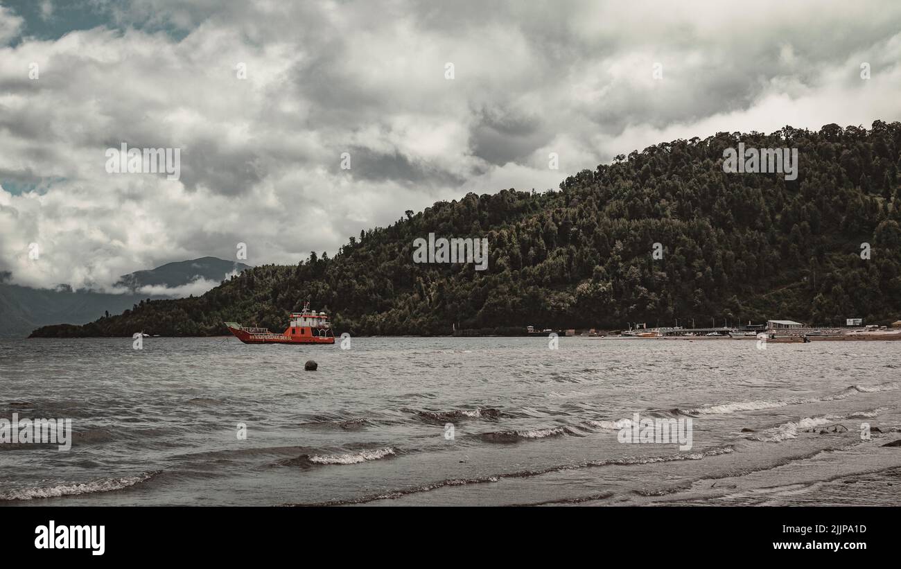 Un bateau près des forêts sur les montagnes par une journée nuageux Banque D'Images