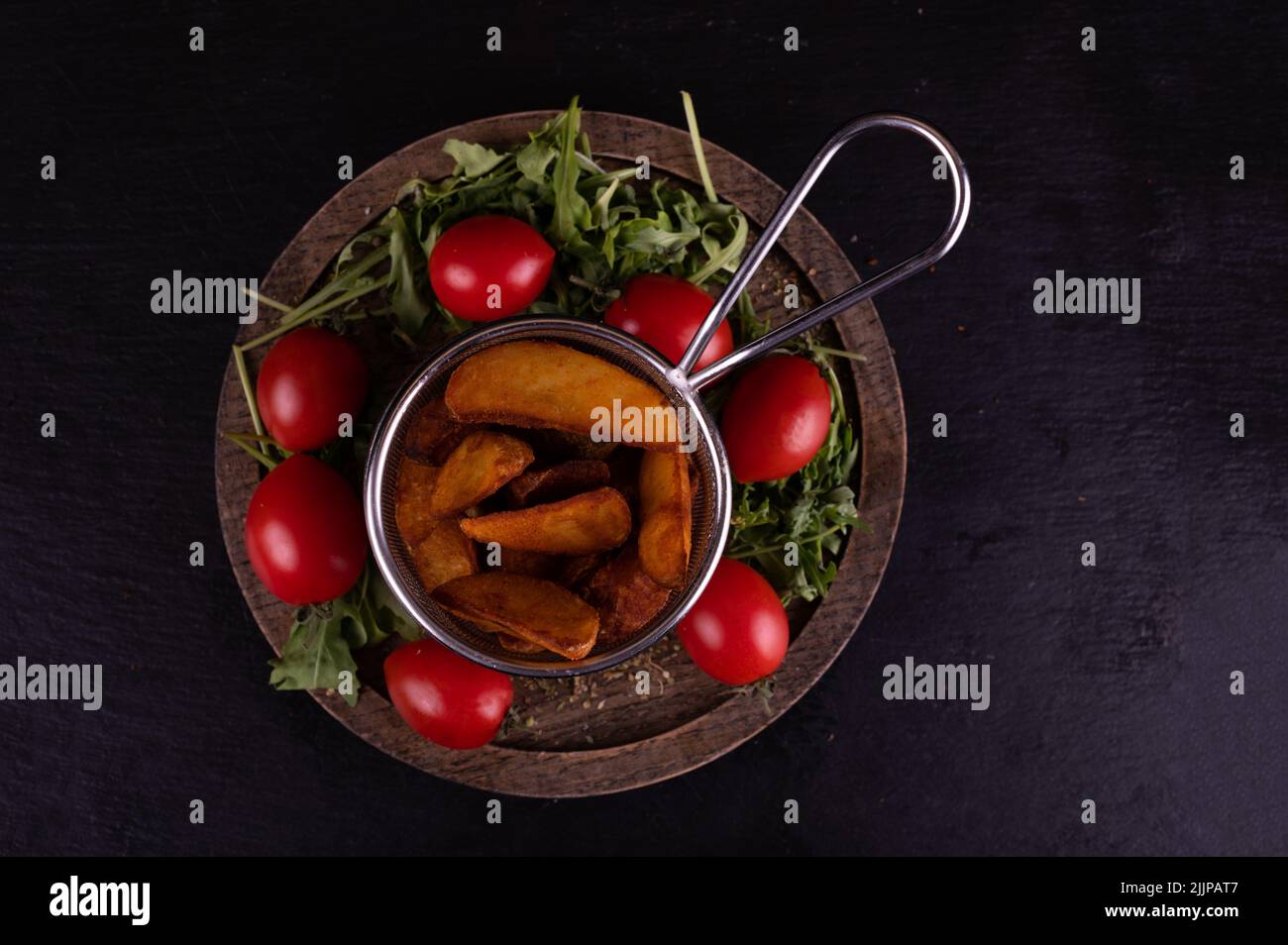 Vue en hauteur d'un panier avec des quartiers de pommes de terre, des tomates cerises et une roquette Banque D'Images