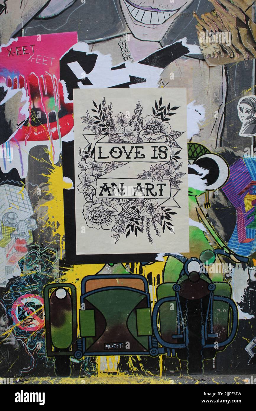 Une photo verticale de graffiti colorés sur le mur dans le streetart de Londres avec un panneau au milieu de "Love is an Art" Banque D'Images
