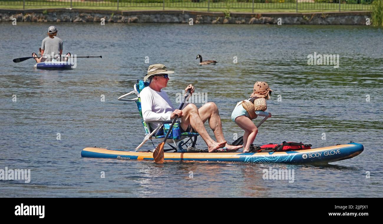 Grand-père et petite-fille flottent sur la rivière Deschutes à Bend, Oregon, sur un paddleboard essayant d'échapper à la vague de chaleur de 100 degrés F qui balaie le Nord-Ouest du Pacifique. Banque D'Images