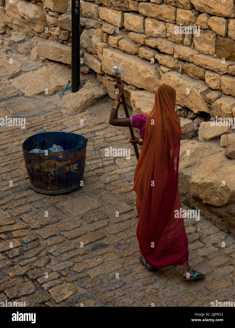 Une vue de la femme dans sari Sweeper nettoyage de la pierre dorée sol dans la rue Banque D'Images