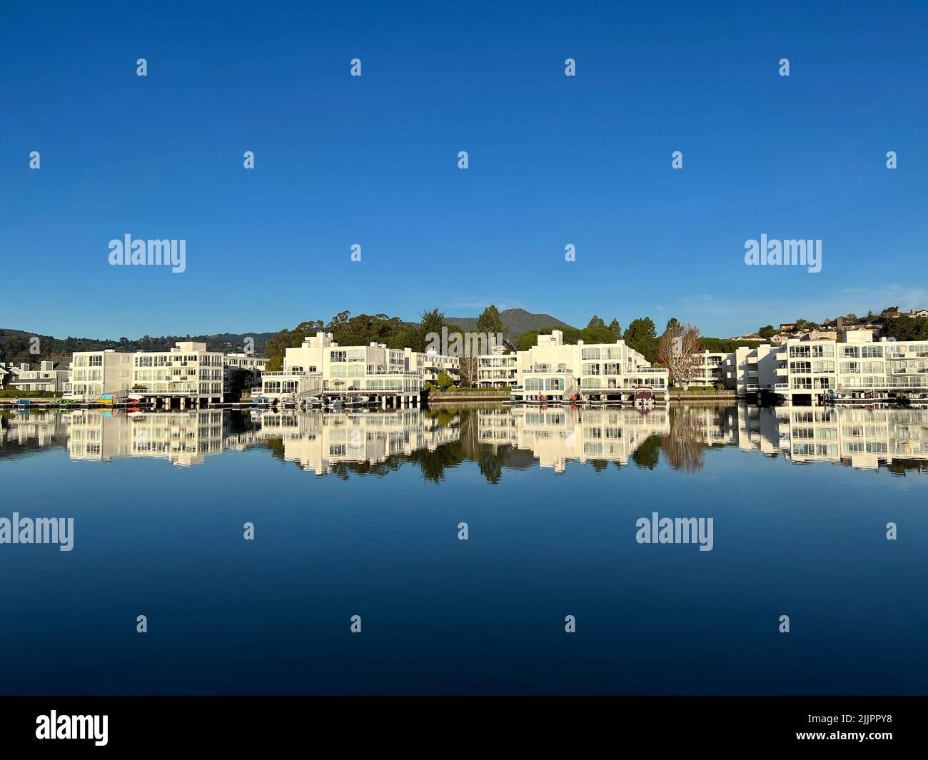 Bâtiments résidentiels blancs et ciel bleu clair réfléchi dans un lac Banque D'Images