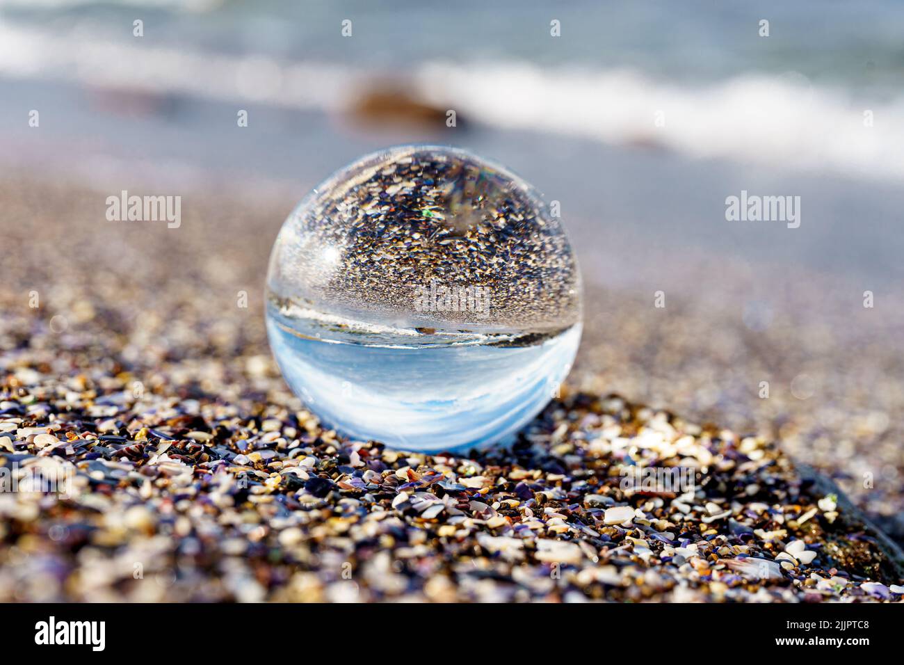 Une boule de verre sur la plage de sable avec le reflet Banque D'Images