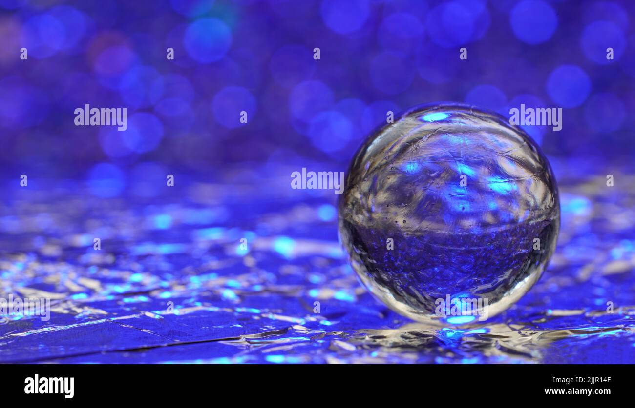 Une boule de verre avec le reflet de la surface bleue et des lumières de bokeh effet sur l'arrière-plan Banque D'Images