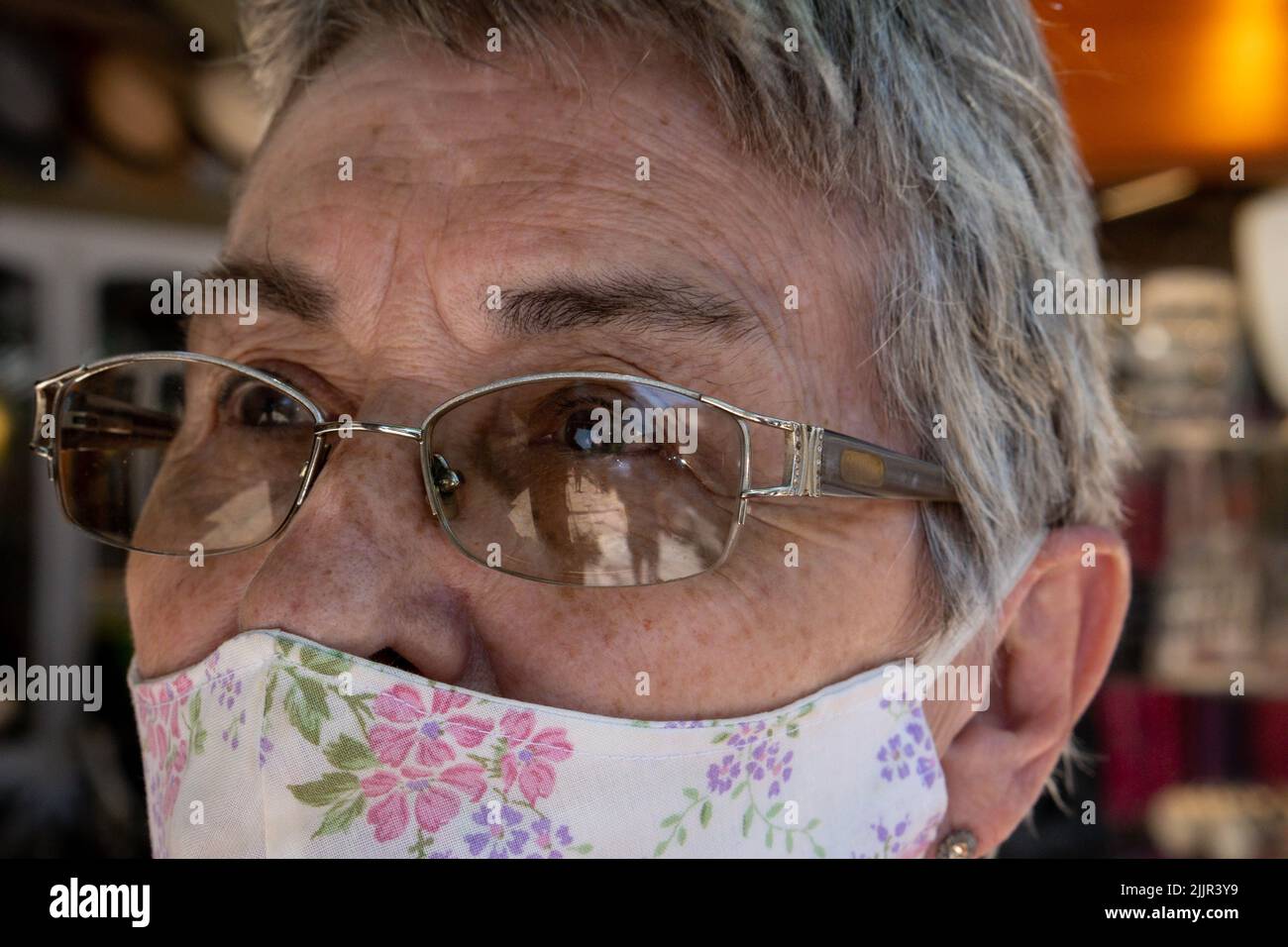 Un portrait d'une femme hispanique âgée avec des lunettes portant un masque facial réutilisable en tissu à l'extérieur par temps ensoleillé Banque D'Images