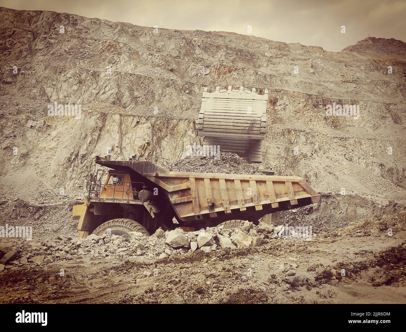 R le taux de fonctionnement de l'exploitation minière du charbon est chargé dans un camion jaune à l'aide d'une pelle hydraulique Banque D'Images