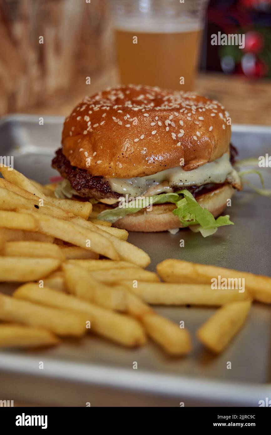 Une photo verticale d'un hamburger de bœuf grillé à la vapeur, aux graines et aux frites sur un plateau dans un restaurant Banque D'Images