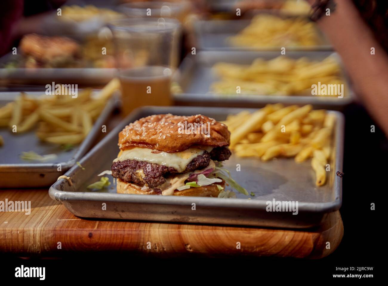 Gros plan d'un hamburger de bœuf grillé à la vapeur, aux graines et aux frites sur un plateau dans un restaurant Banque D'Images