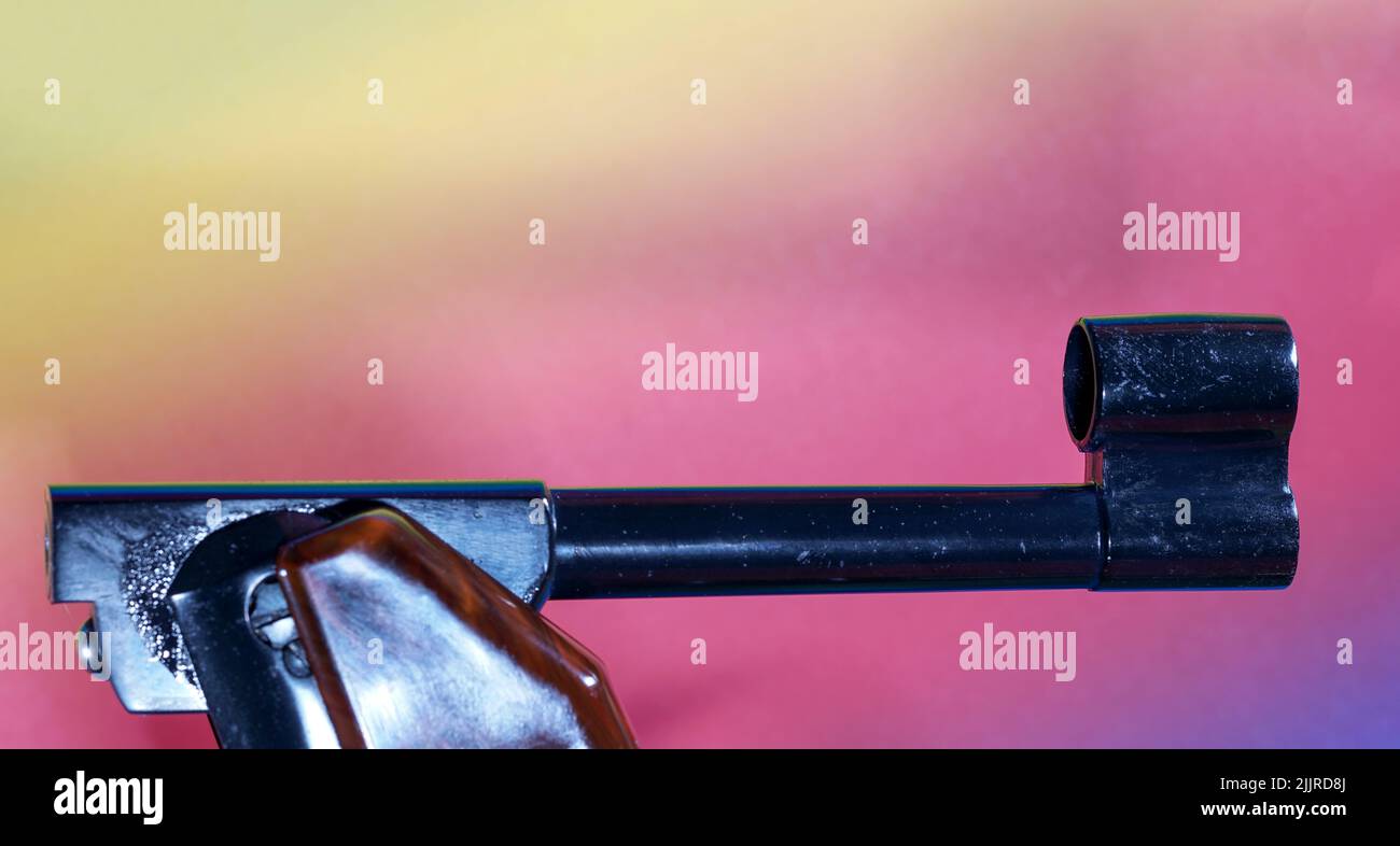 Un gros plan d'une arme à feu avec canon à fumée sur un fond coloré Banque D'Images