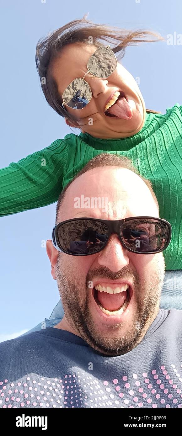 Une photo verticale d'un couple de voyageurs heureux faisant le selfie contre un ciel bleu Banque D'Images