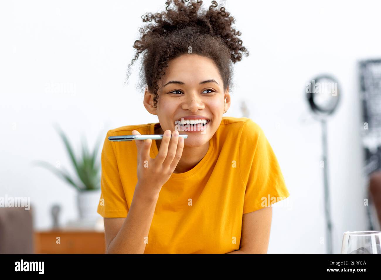 Jeune femme afro-américaine envoyant un message vocal par téléphone portable Banque D'Images