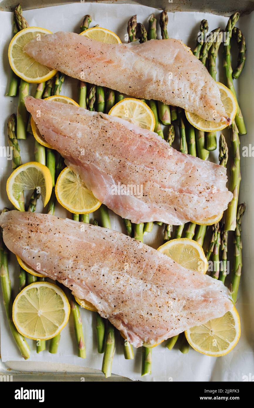 Sébaste du pacifique cru sur un lit d'asperges et de pignons de citron, dîner de la poêle à feuilles. Préparer de la truite Amandine. Banque D'Images