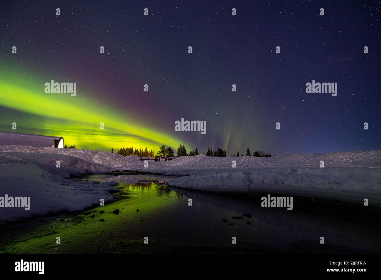 Une vue panoramique des lumières polaires verdoyantes de l'Aurora Borealis qui se reflète sur la rivière - le ciel nocturne suédois Banque D'Images