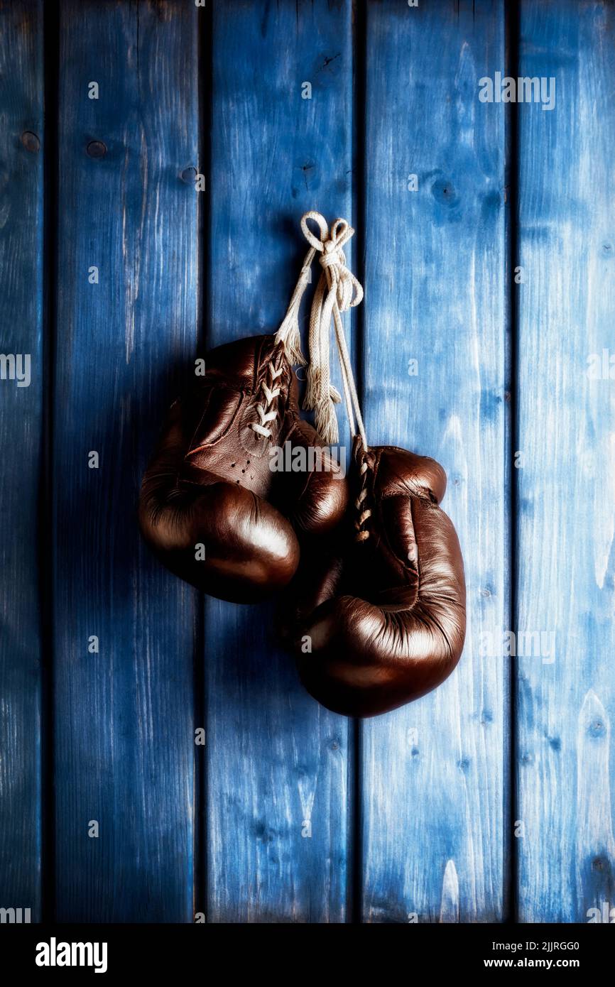 vieux gants de boxe suspendus devant un mur en bois bleu rustique Banque D'Images