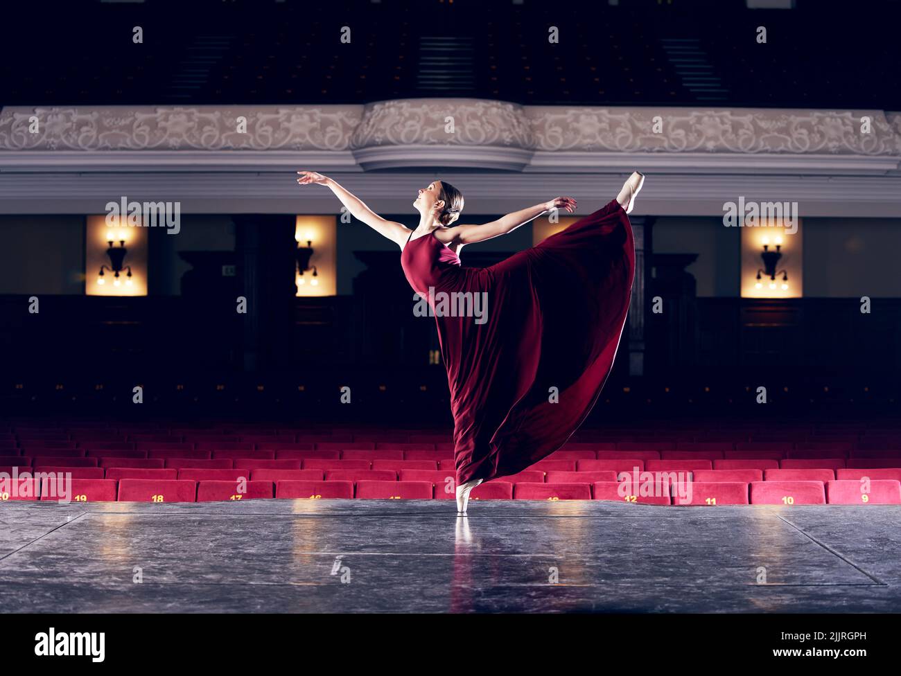 Allez dur pour le dernier étirement. Une ballerine exécutant sa routine dans un théâtre. Banque D'Images