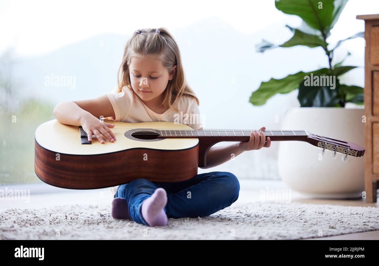 Jolie Petite Fille À Pratiquer Un Nouveau Son Sur Une Guitare À La Maison  Banque D'Images et Photos Libres De Droits. Image 22568632
