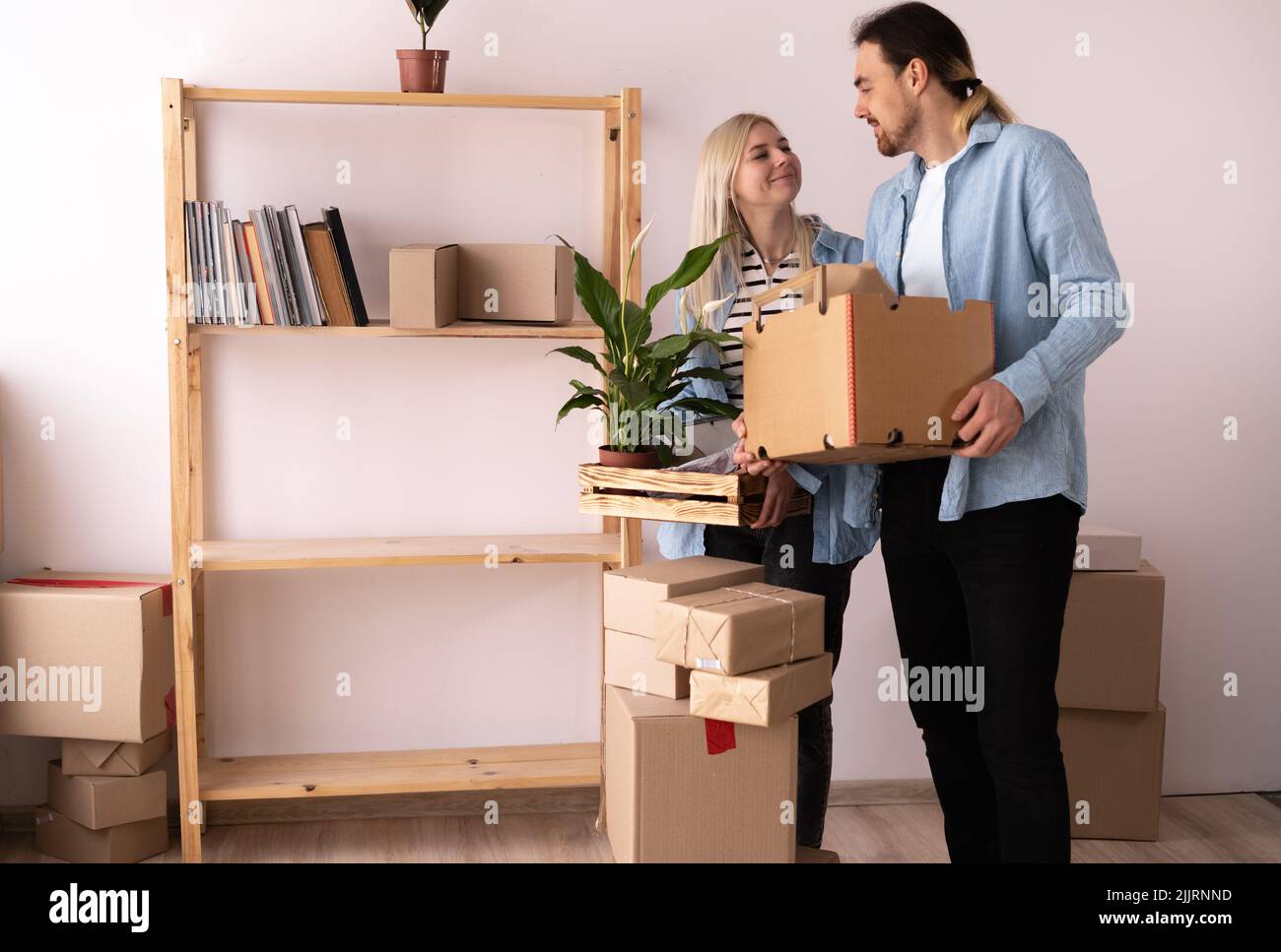 Couple déménapose dans un nouvel appartement. Jeune couple avec des boîtes se déplaçant dans le nouvel appartement. Lot de cartons d'emballage autour d'eux. Nouvelle maison et déplacement Banque D'Images