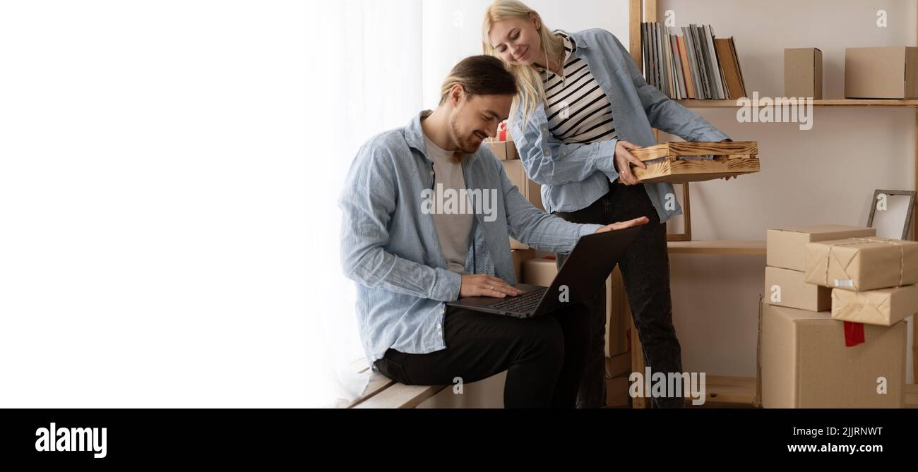 Un jeune couple qui se déplace dans une nouvelle maison se détendant assis à l'aide d'un ordinateur portable, souriant heureux de déménager dans un nouvel appartement Banque D'Images