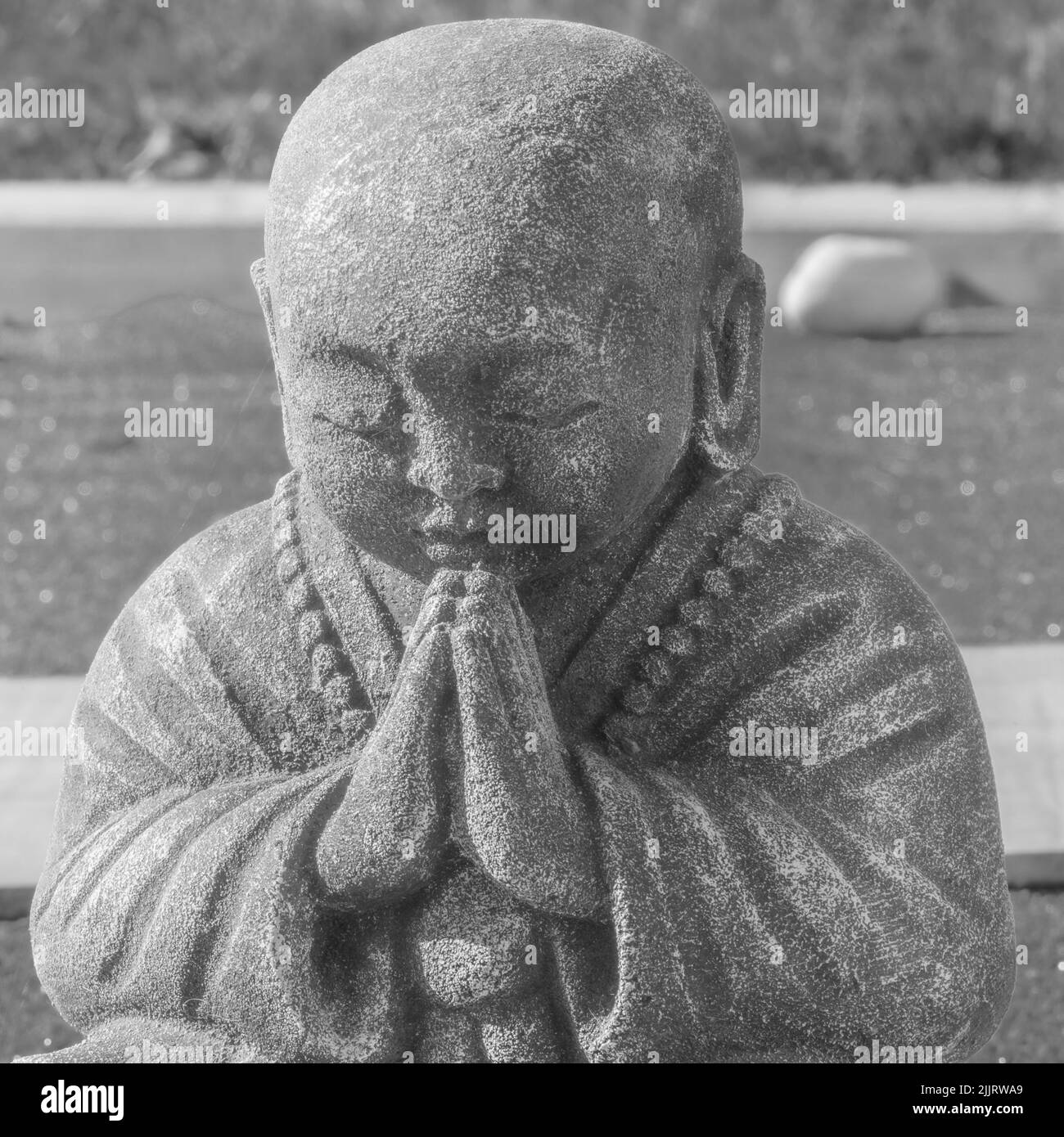 Statue en pierre d'un moine bouddhiste priant. Banque D'Images