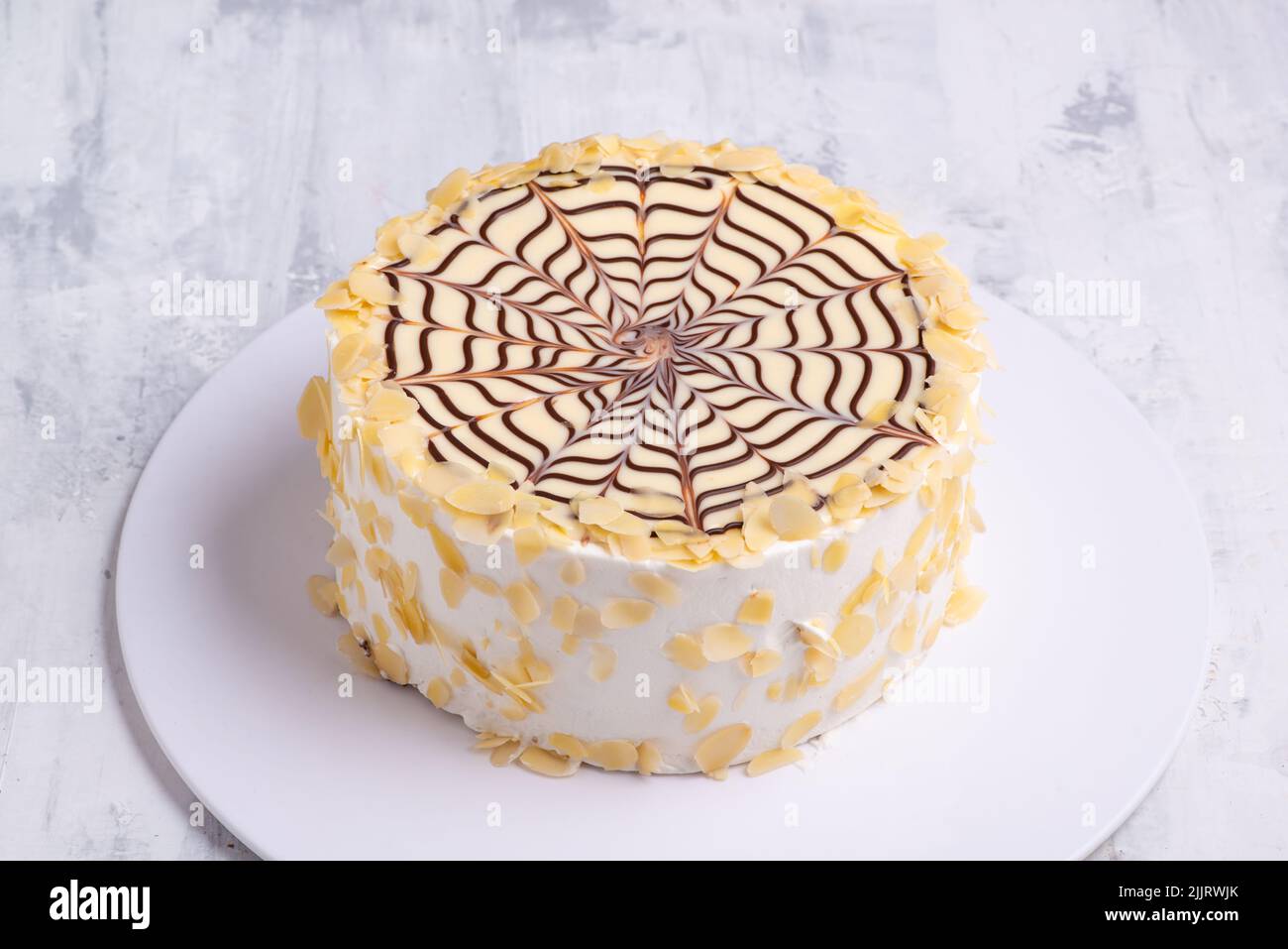 Un gâteau fait avec des couches de pâte feuilletée remplie de crème fraîche et d'araignée au chocolat sur une plaque blanche sur une surface en marbre blanc Banque D'Images