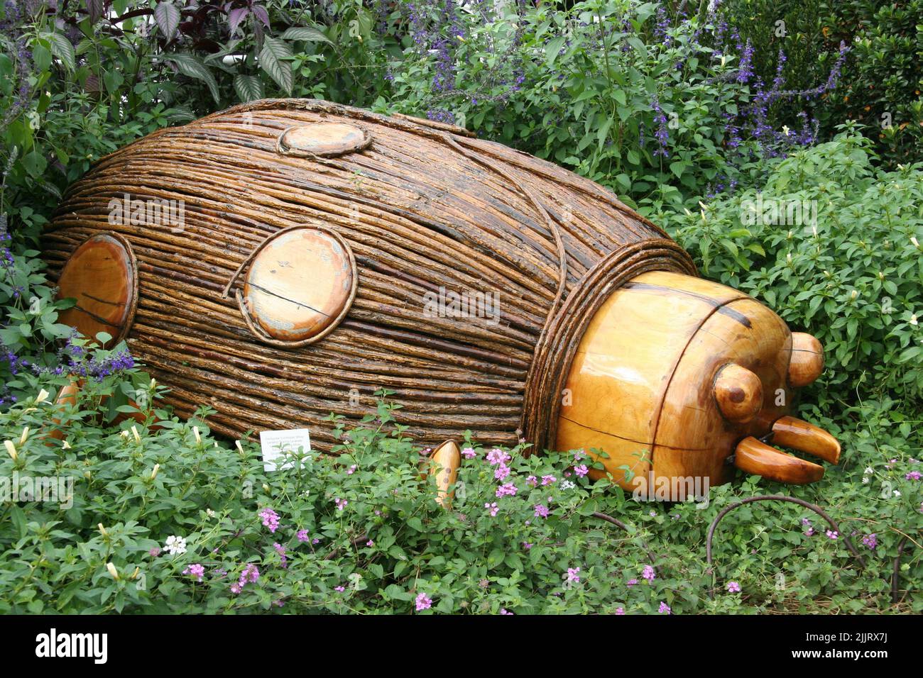 Une belle photo d'une grande sculpture en bois d'une coccinelle parmi l'herbe verte dans le jardin pendant la journée Banque D'Images