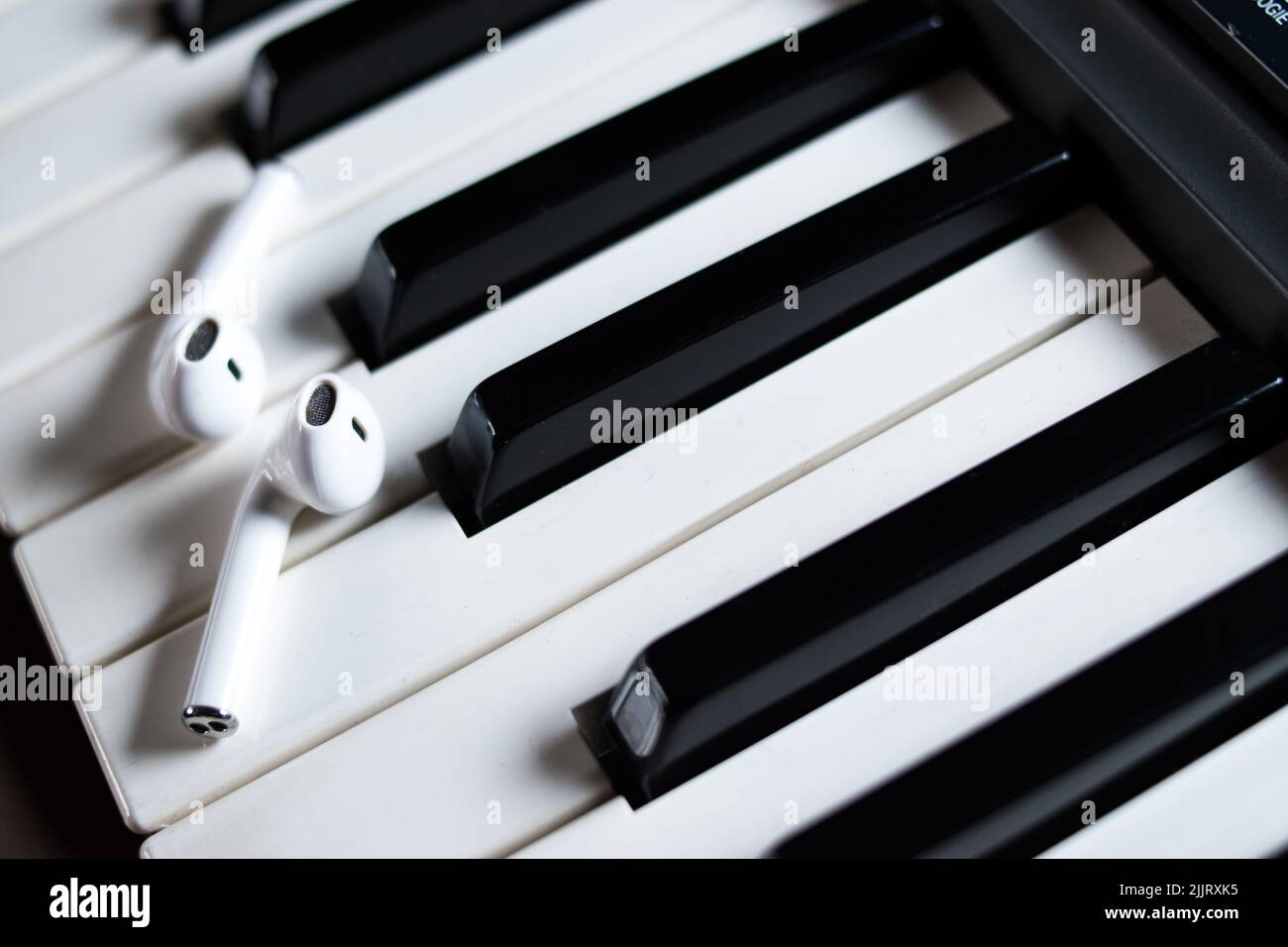 Un gros plan des écouteurs sans fil sur les touches de piano noir et blanc Banque D'Images