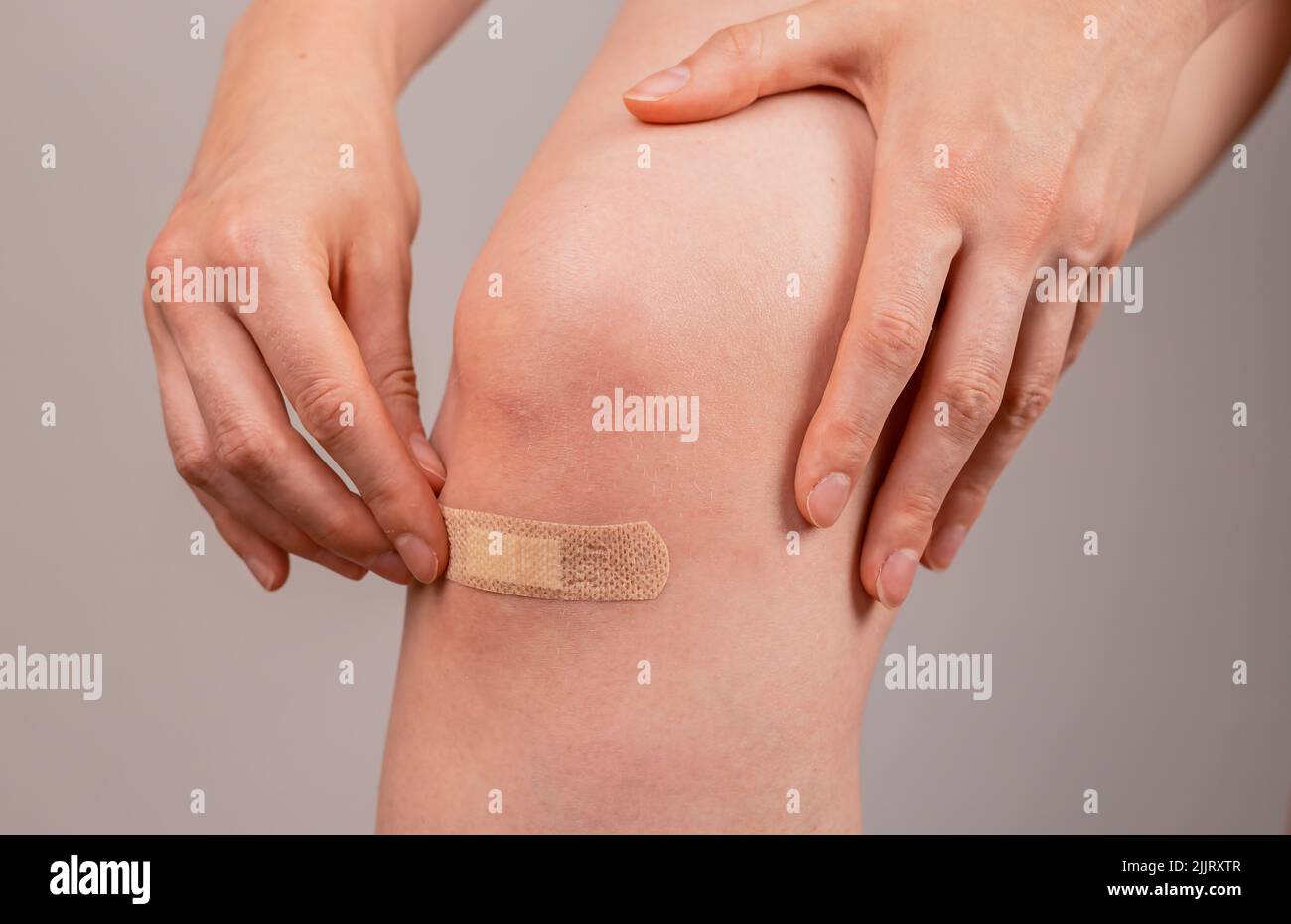 Femme appliquant du plâtre médical sur le genou. Concept de premiers soins. Coupures, abrasions et cicatrisation légère des plaies. Prévention des infections. Photo de haute qualité Banque D'Images
