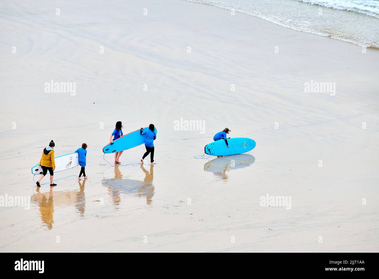 Les surfeurs débutants avec leurs planches sur la plage Great Western, Newquay, Cornwall, Angleterre, un jour de pluie. Banque D'Images
