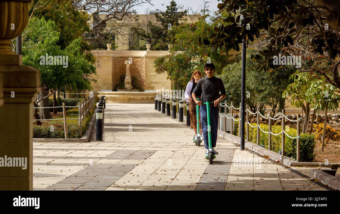 Un jeune couple qui profite d'une promenade en scooter électrique dans les jardins botaniques d'Argotti Banque D'Images