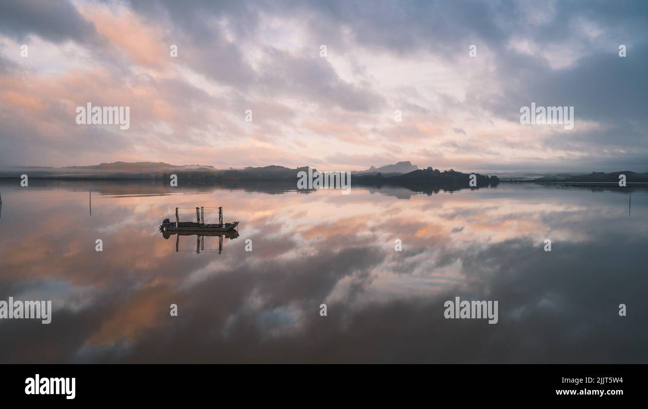 La baie de Matauri au coucher du soleil avec des nuages reflétés dans l'eau, Far North District, Nouvelle-Zélande Banque D'Images