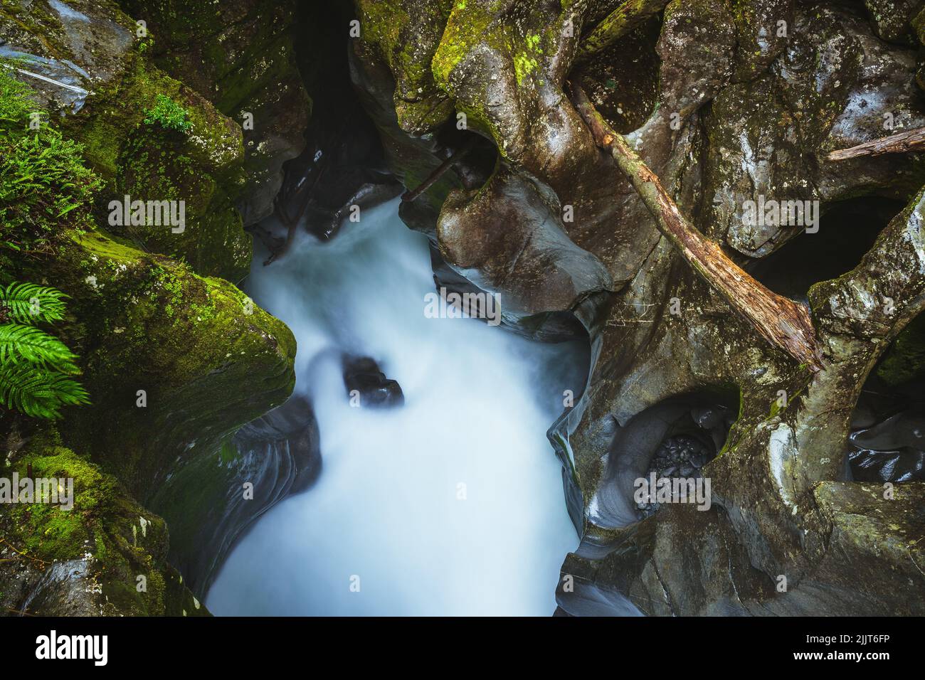 Photo en grand angle de roches vertes déchiquetées entourant un ruisseau bleu-blanc frais à Milford Sounds, en Nouvelle-Zélande Banque D'Images