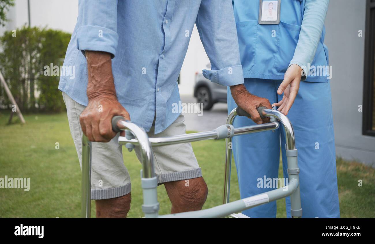 Personne âgée âgée, patient qui fait une thérapie physique avec un soignant. Les femmes de soignant attirantes aident et soutiennent le valin de pratique masculin plus âgé Banque D'Images