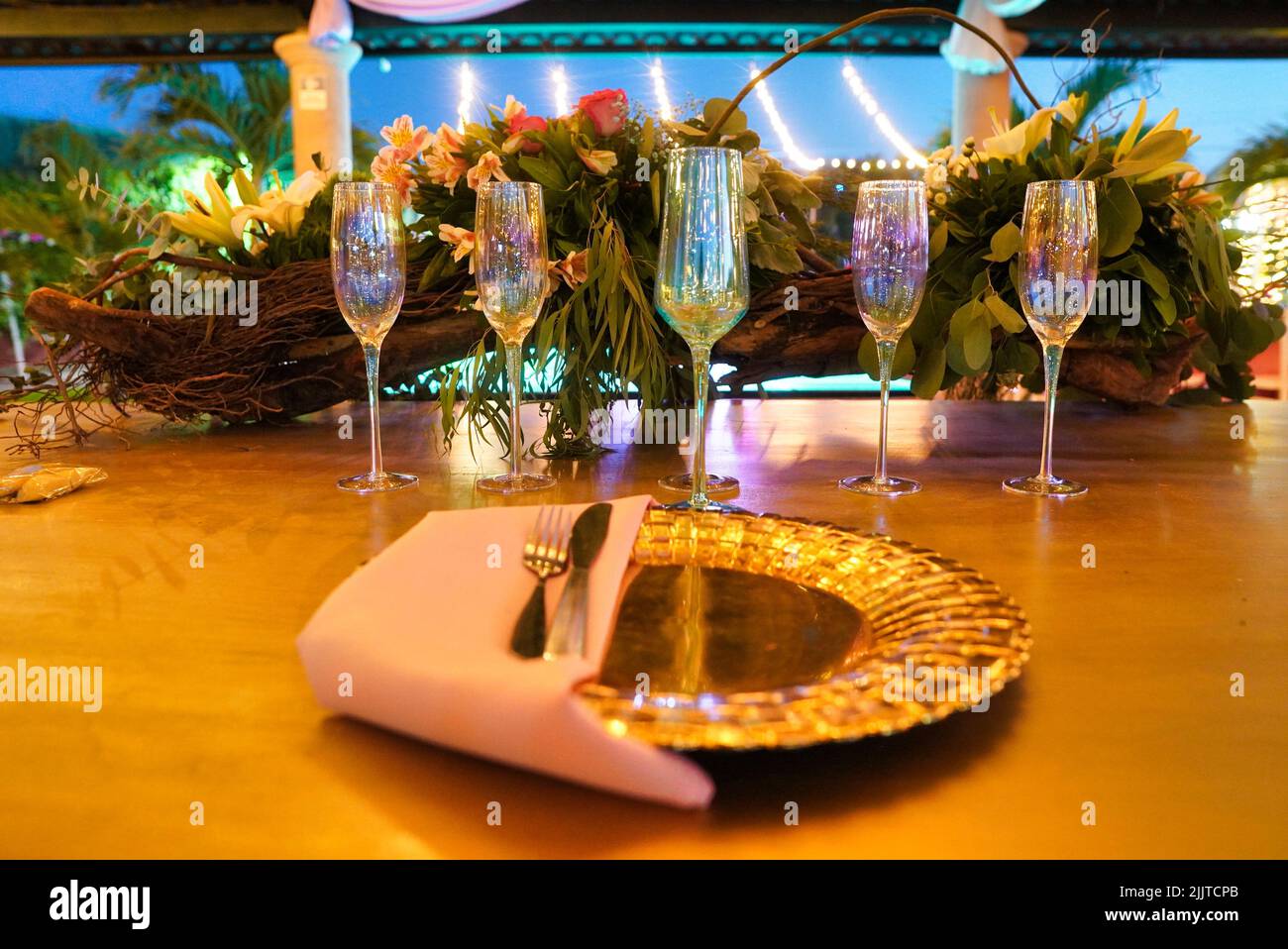 Une table avec Une assiette dorée et des verres à champagne irisés lors d'une réception de mariage Banque D'Images