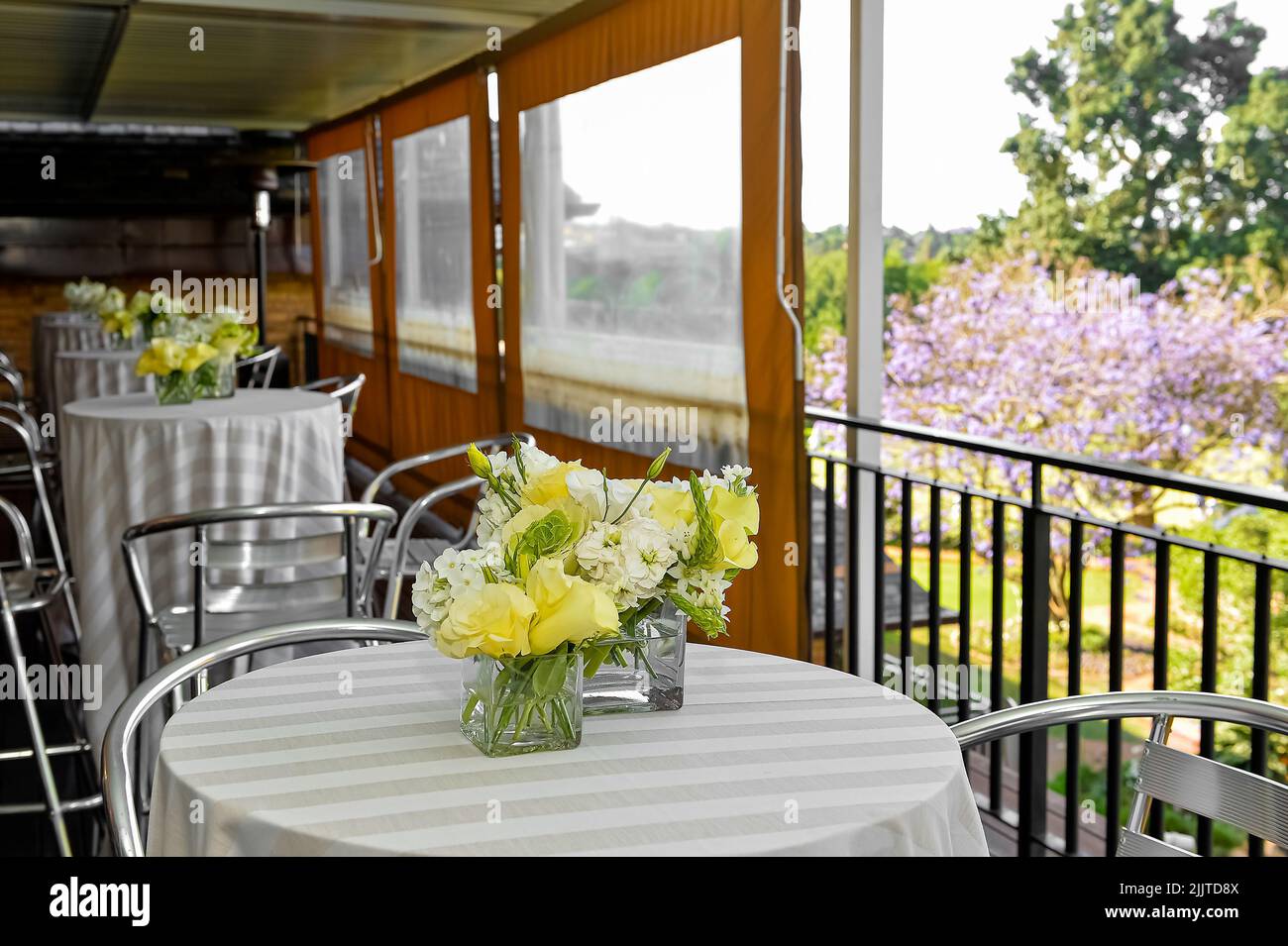 Belles tables de café avec fleurs et vue sur un jardin ensoleillé Banque D'Images