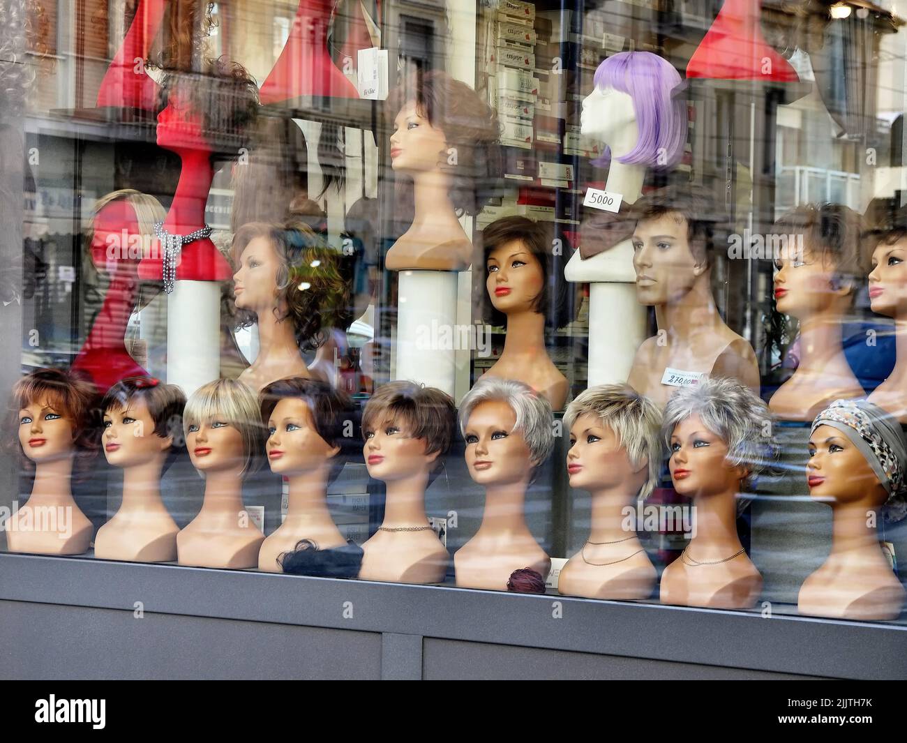 Une belle photo d'une fenêtre de magasin de perruques avec différents types de perruques Banque D'Images