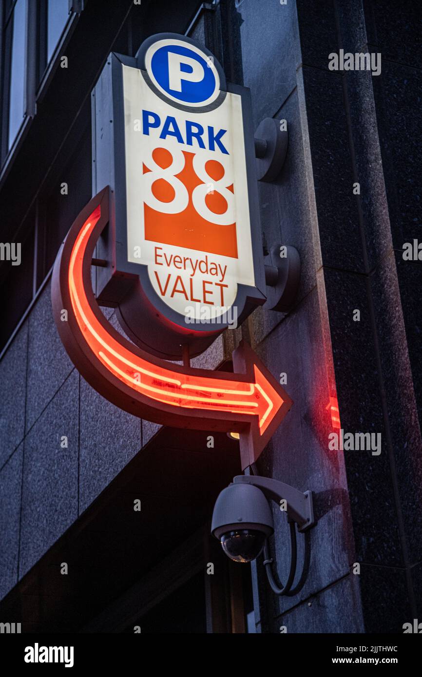 Un panneau de stationnement avec une flèche rouge néon sur un bâtiment Banque D'Images