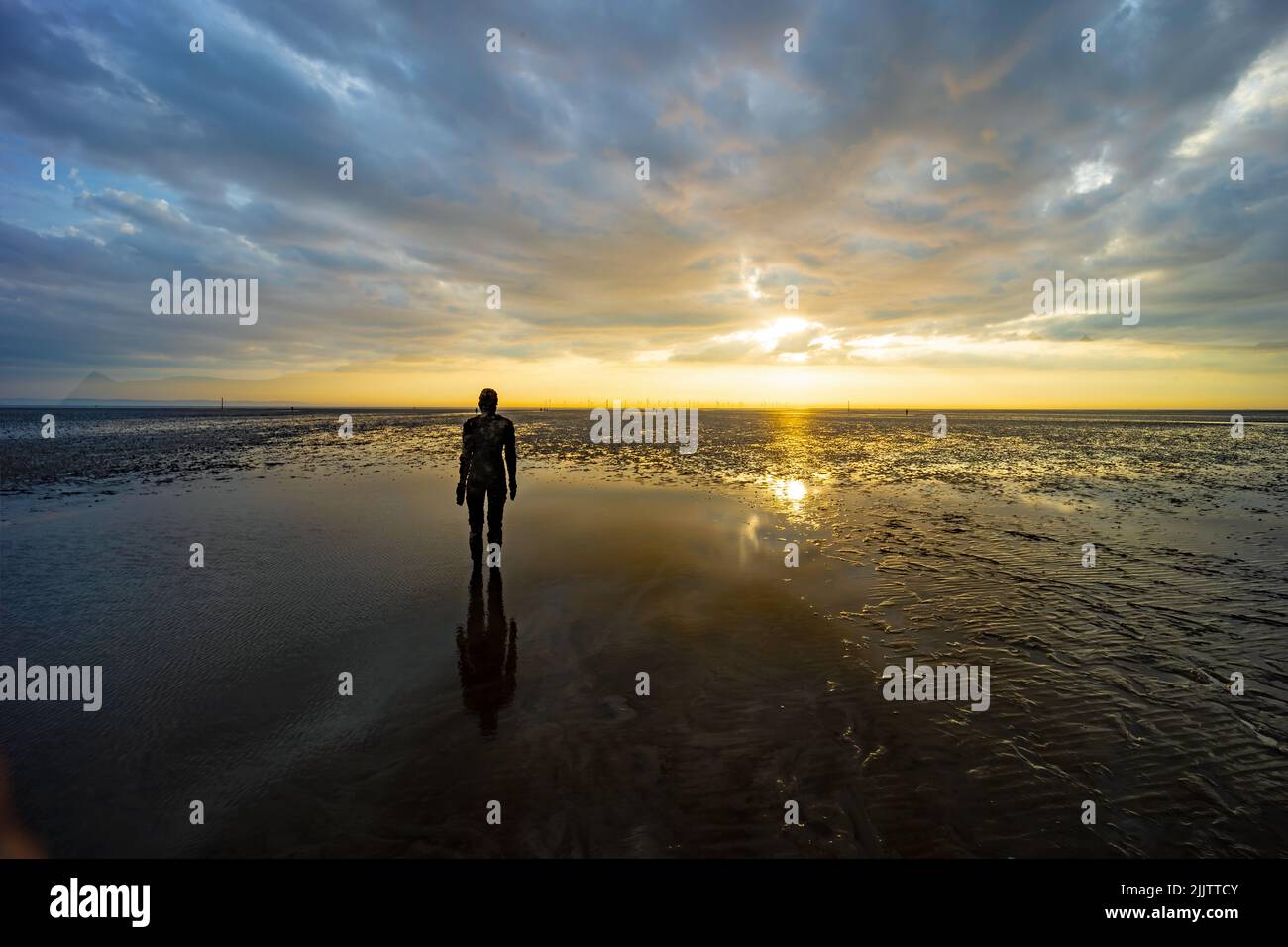 Une belle photo d'une sculpture à un autre endroit de Crosby Beach, au Royaume-Uni, au coucher du soleil nuageux Banque D'Images