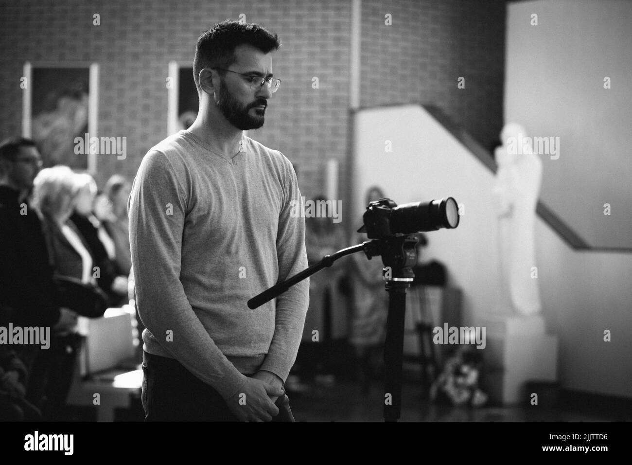Photo en noir et blanc d'un beau cinéaste masculin en poste avec une caméra Sony en monopied Banque D'Images