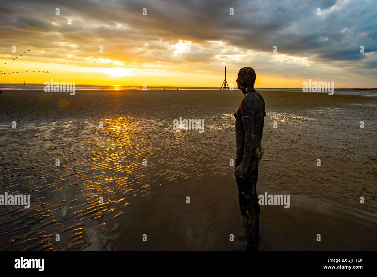 Une belle photo d'une sculpture à un autre endroit de Crosby Beach, au Royaume-Uni, au coucher du soleil nuageux Banque D'Images