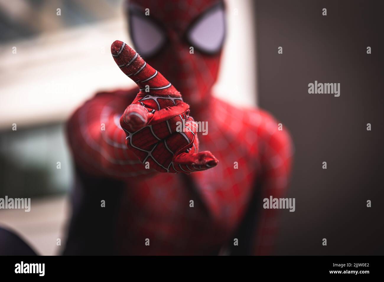https://c8.alamy.com/compfr/2jjw0e2/un-gros-plan-de-spider-man-regardant-l-appareil-photo-avec-sa-main-devant-dans-un-arriere-plan-flou-2jjw0e2.jpg