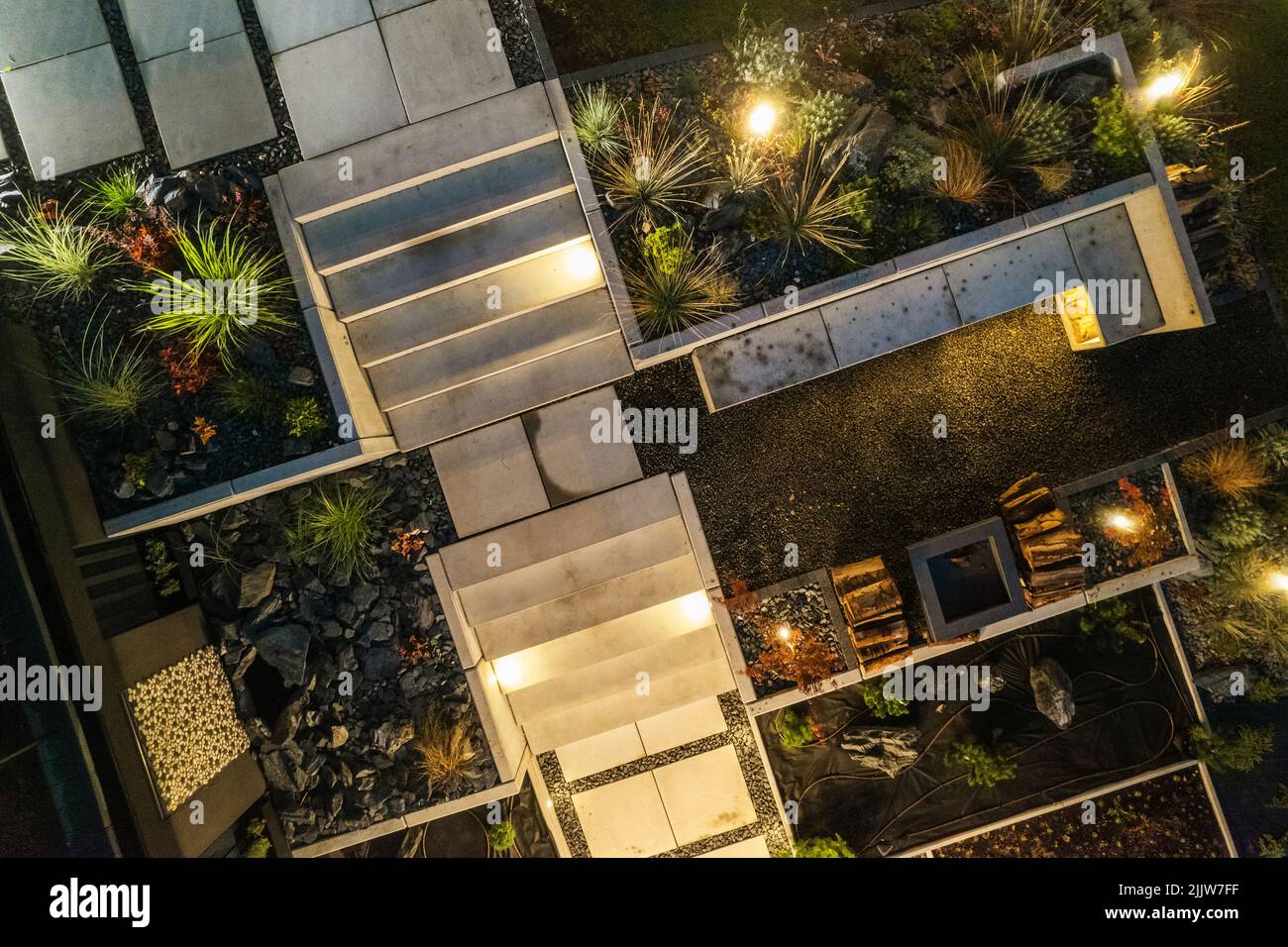 Vue aérienne de nuit d'un jardin moderne avec des éléments en béton architectural et une cheminée. Jardin éclairé par des lumières à DEL installées en peu Banque D'Images
